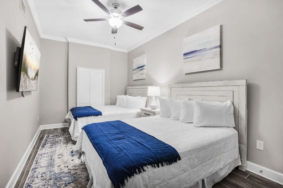 Rest on one of the two queen beds beneath coastal art in this guest suite, with a lamp ready for late-night reading