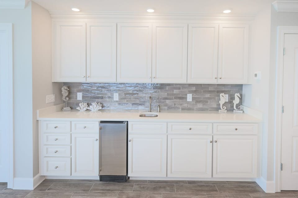 Retrieve chilled drinks from the compact fridge and admire seahorse decor against the glossy tile backsplash