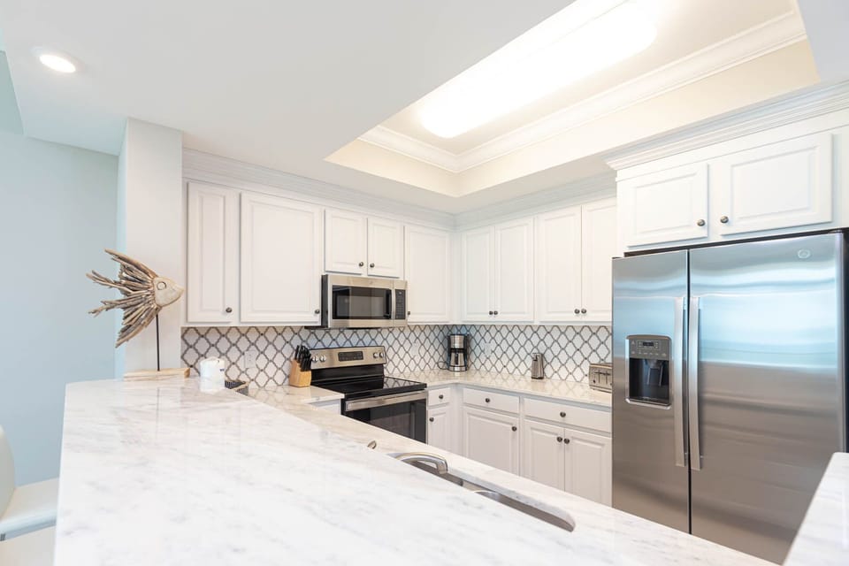 Prepare meals in this kitchen with elegant cabinetry, stainless appliances, and stylish backsplash