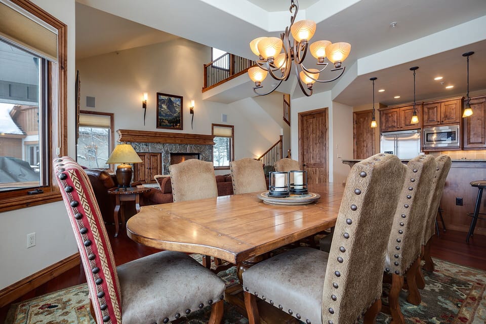 Gather around this stunning dining table where warm wood meets elegant lighting for memorable meals with loved ones.