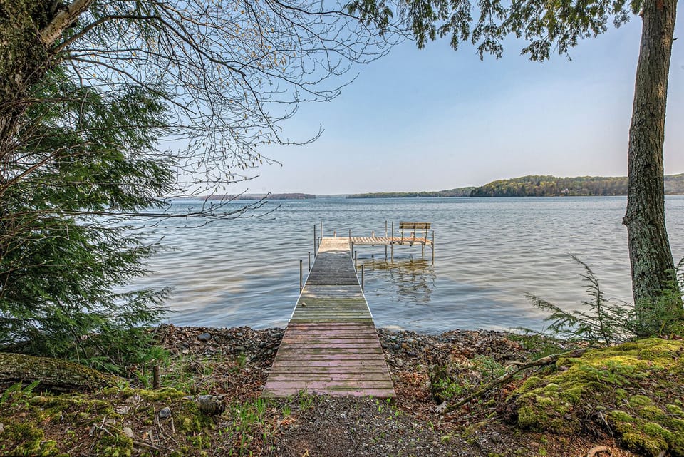 - Lakeside dock stretching over calm clear water views - Perfect spot for sunrise photos fishing or quiet moments - Scenic shoreline offering peaceful outdoor lake access