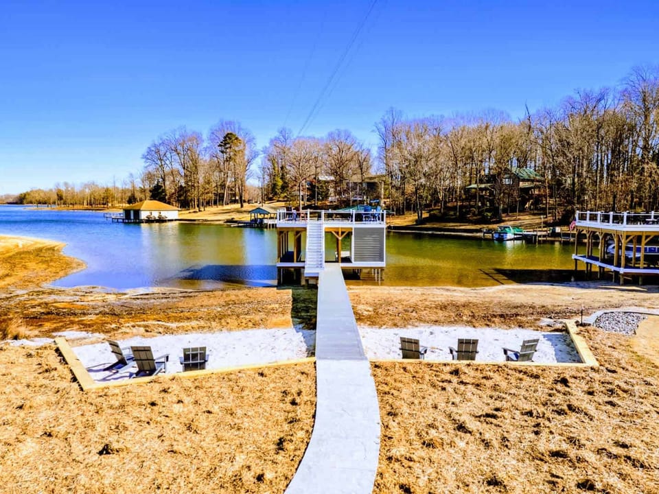 Your Private Beach Landing – Adirondacks in the sand, calm water ahead, and a dock just steps away.