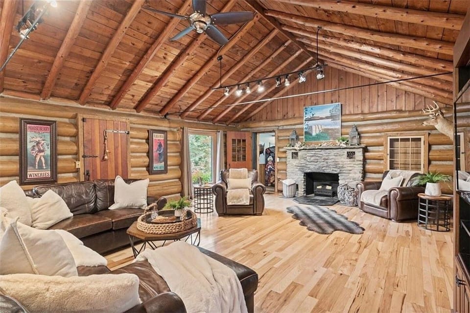 Immerse yourself in the warmth of this inviting, rustic-chic living space, complete with a cozy stone fireplace, rich leather sofas, Smart TV, and striking log cabin walls that beckon you to relax and stay awhile.