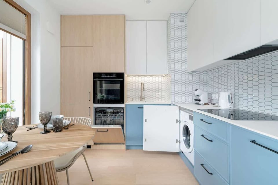A kitchen countertop featuring a white kettle, coffee maker, and hexagonal tiles on the wall.

