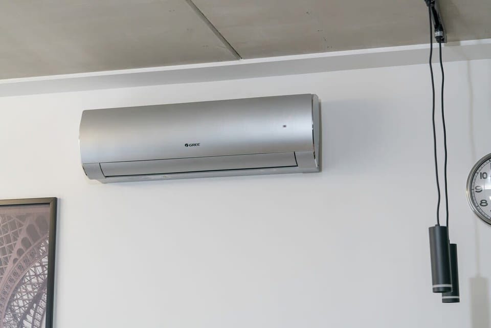 A wall-mounted air conditioning unit in silver, set against a gray wall, providing both cooling and a modern accent.
