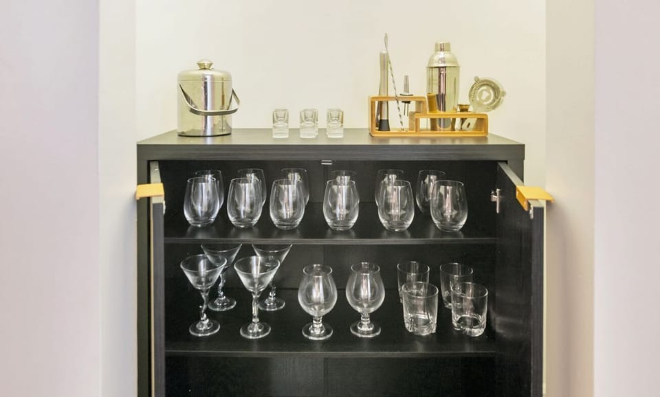 A modern bar cabinet stocked with a variety of glassware and cocktail tools for entertaining.