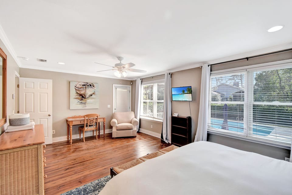 Master Bedroom with Desk, TV, and Pool View – Beach Crew Cottage - A second view of the master shows the writing desk, reading chair, and TV—plus direct views of the private pool just outside. It’s equal parts comfort, privacy, and a little bit of bragging rights.
