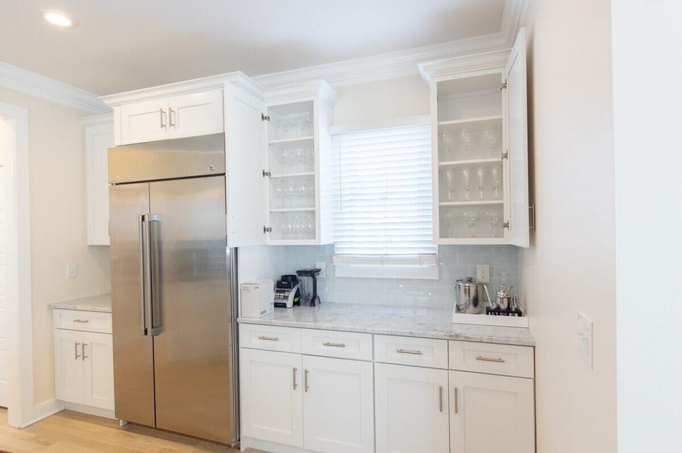 Kitchen - The modern design is highlighted by sleek white cabinetry and a charming blue subway tile backsplash, creating a bright and inviting atmosphere for cooking and socializing. 