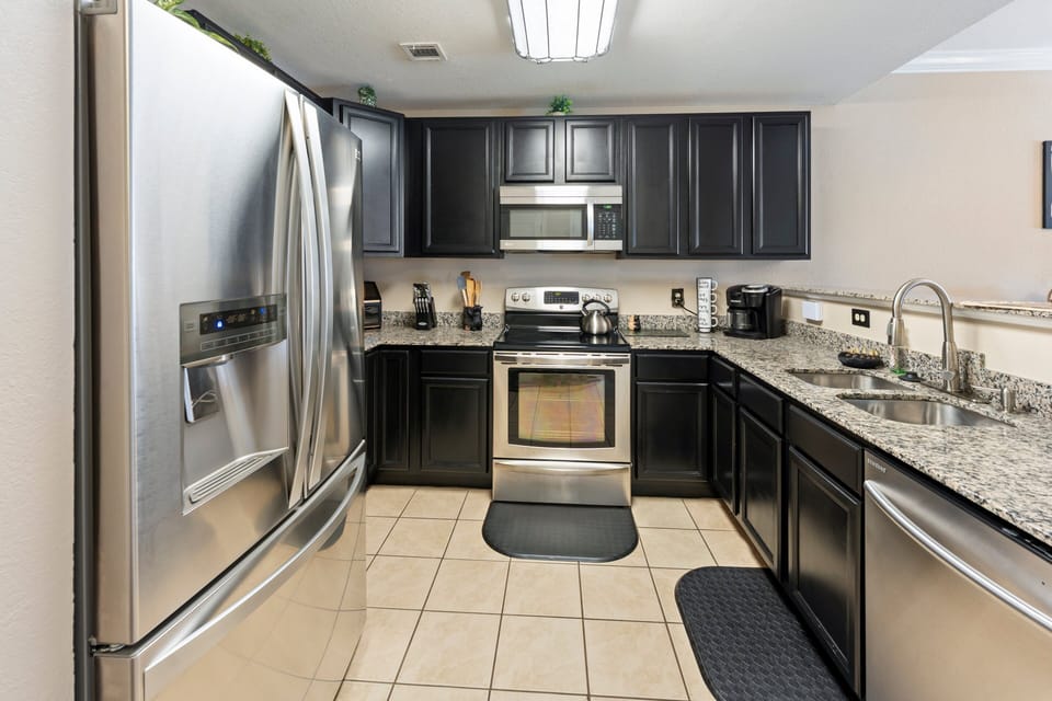 Fully equipped kitchen featuring dark cabinetry, stainless steel appliances, granite countertops, and all cooking essentials at A Sleepy Bear Getaway condo in Pigeon Forge, Tennessee