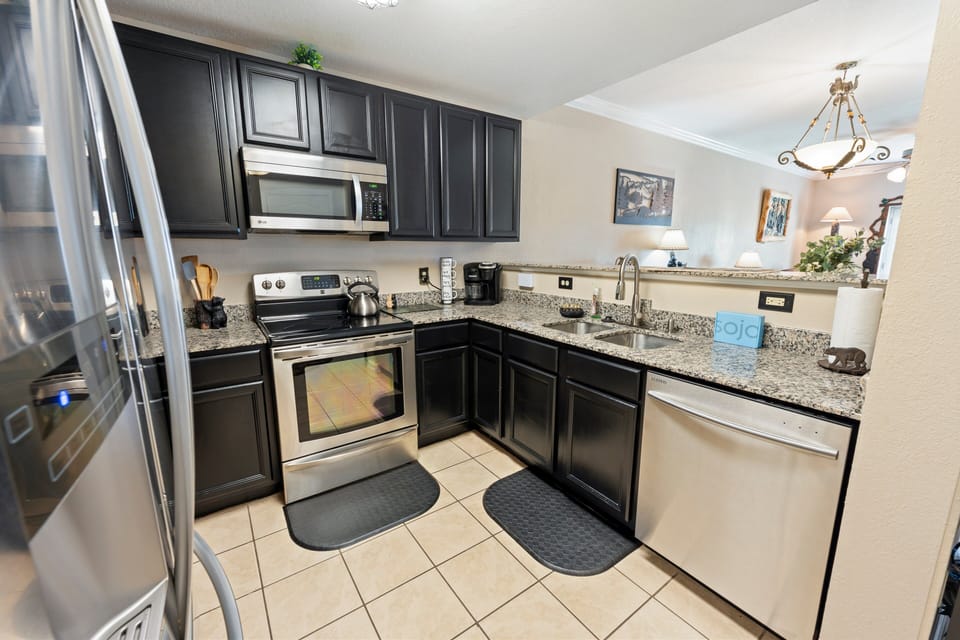 Modern kitchen with stainless steel refrigerator, microwave, dishwasher, and granite countertops at A Sleepy Bear Getaway condo in Pigeon Forge, Tennessee