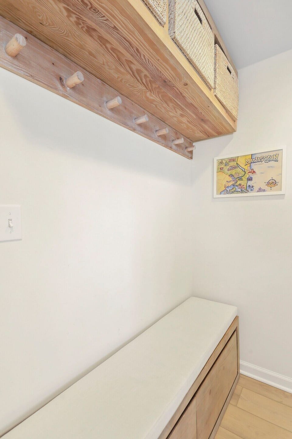 This space features custom wooden hooks and shelves for easy storage, plus a comfortable built-in bench with a cushion.