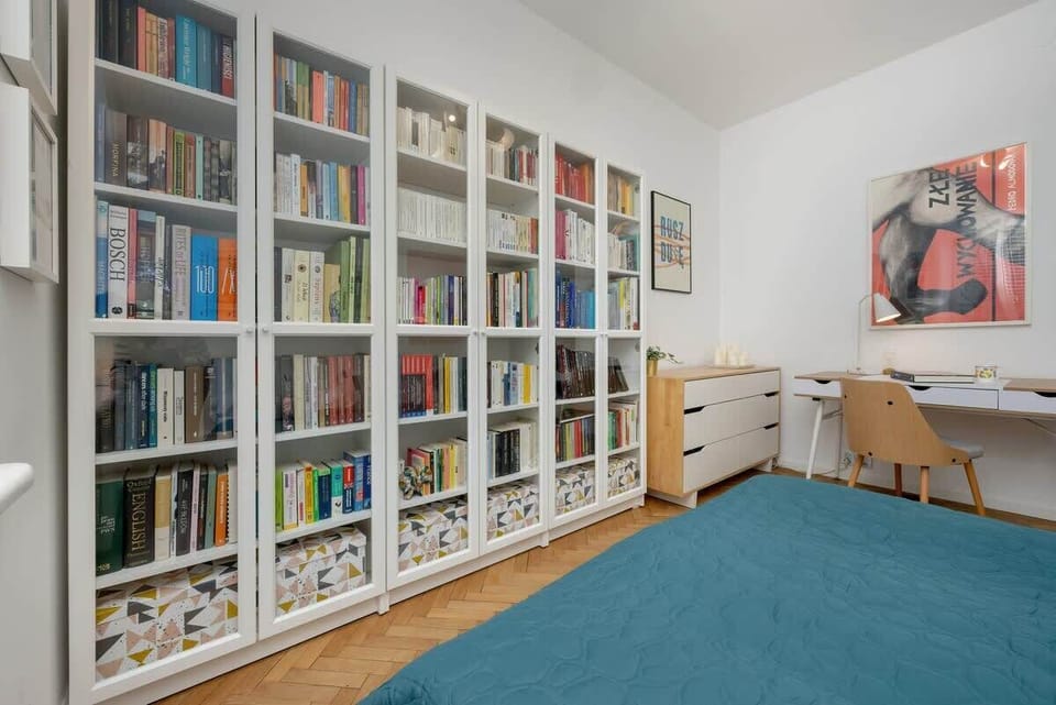 A bright reading nook with bookshelves, a cozy chair, and large windows.

