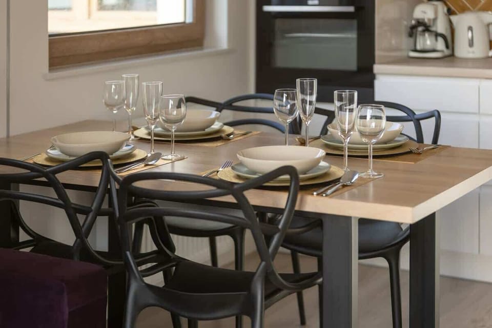 A close-up of the dining space, featuring a dark wooden table set for four, with elegant place settings. It seamlessly blends into the living room, providing a modern and functional space for meals.