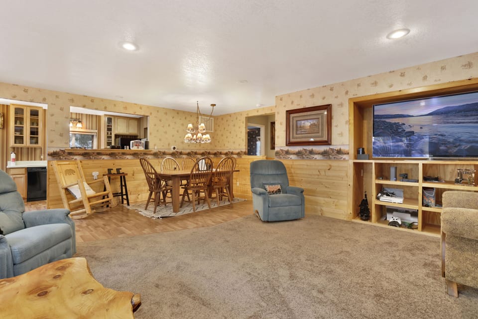 Cozy mountain living room with a stone fireplace, comfy seating, and smart TV—perfect for relaxing evenings, movie nights, and warm cabin vibes after outdoor adventures.