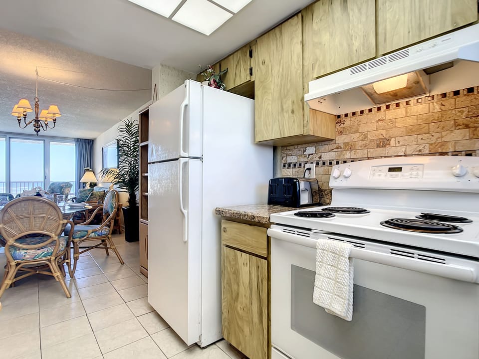 Compact kitchen with modern appliances, stylish backsplash, and a cozy dining area.