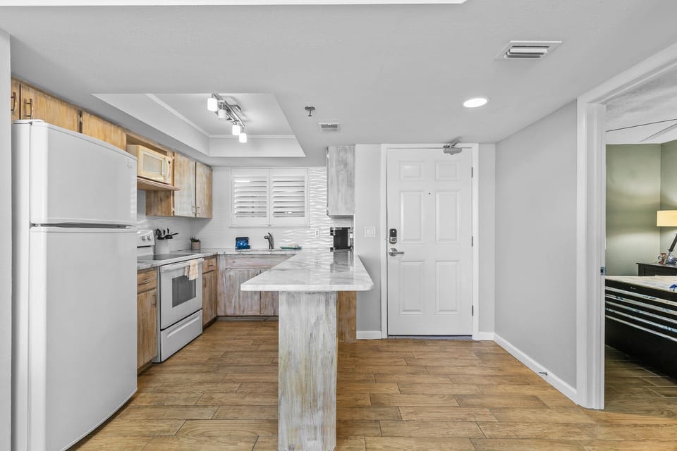 Fully equipped kitchen with rustic cabinets, marble-style countertops, and modern appliances for all your cooking needs.