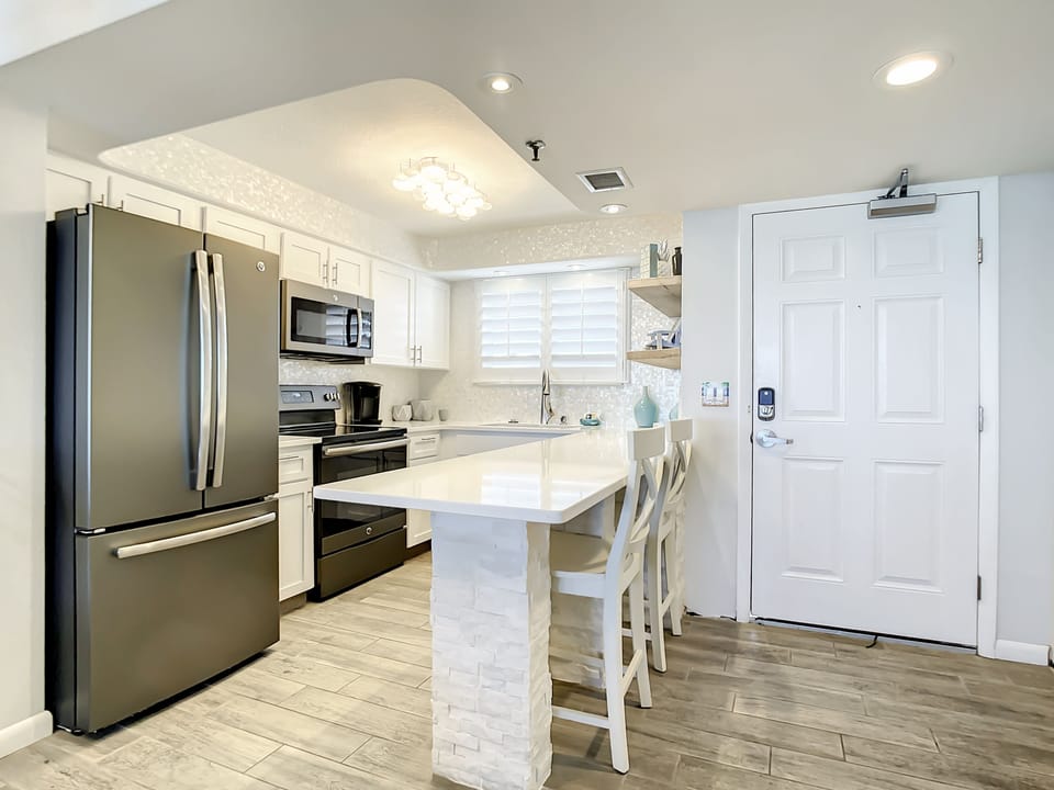 Fully equipped kitchen with stainless steel appliances, bar seating, and ample countertop space for dining and prep.