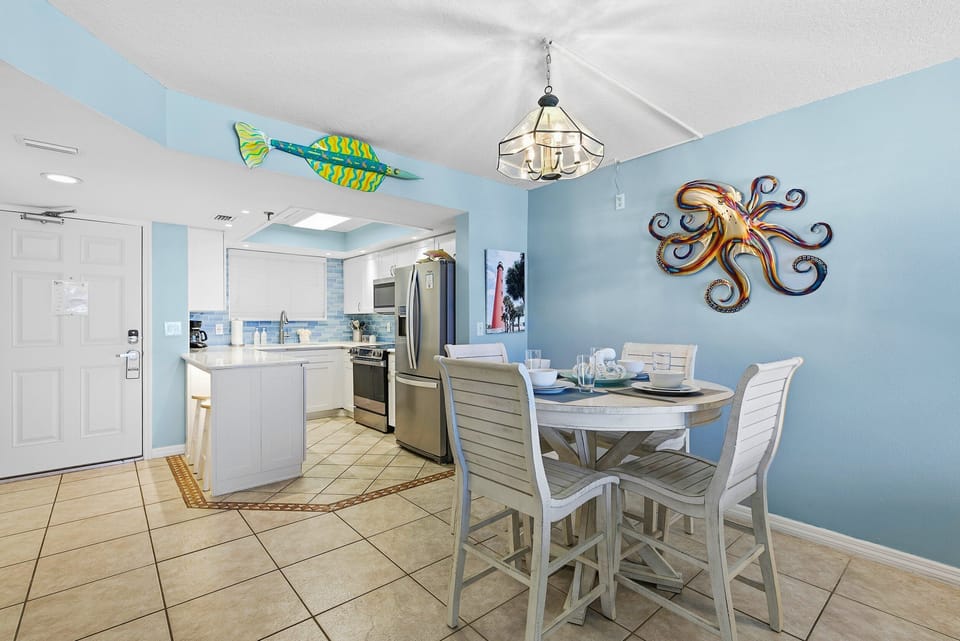 Enjoy this bright dining area and fully equipped kitchen with charming coastal décor. Perfect for your beach stay, gather for meals and relax in a light-filled space just minutes from the ocean.