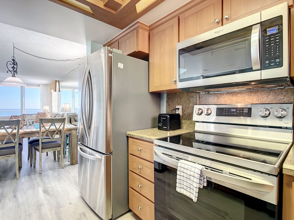 Fully equipped kitchen with stainless steel appliances, granite countertops, and an open layout, perfect for cooking with a view.
