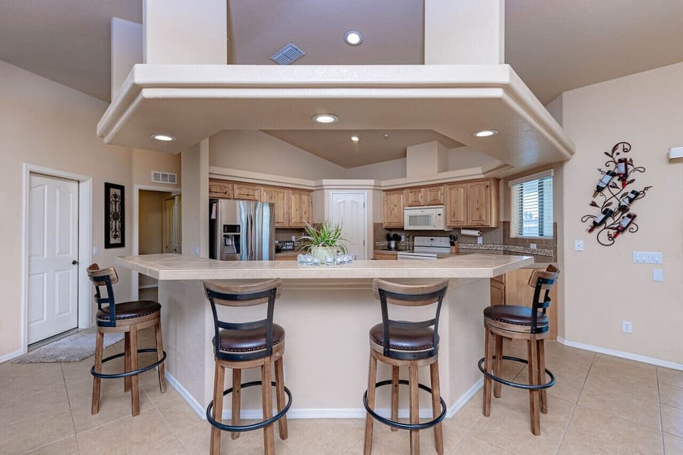 Fully stocked kitchen with cooking supplies and four barstools.