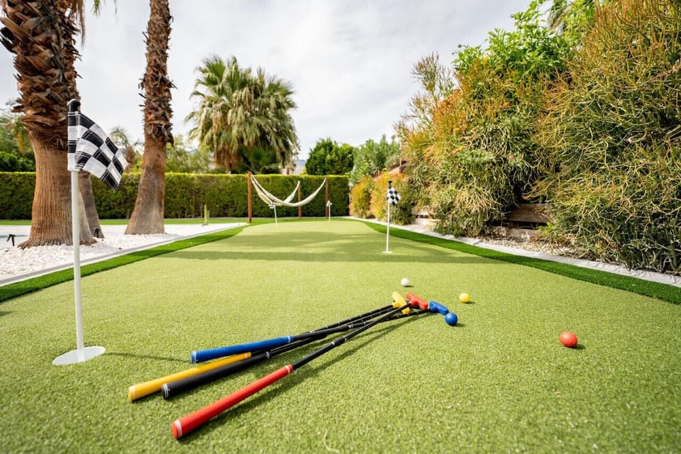 Lush putting green set among palms and greenery—grab a club, take aim, and enjoy a relaxed outdoor game.