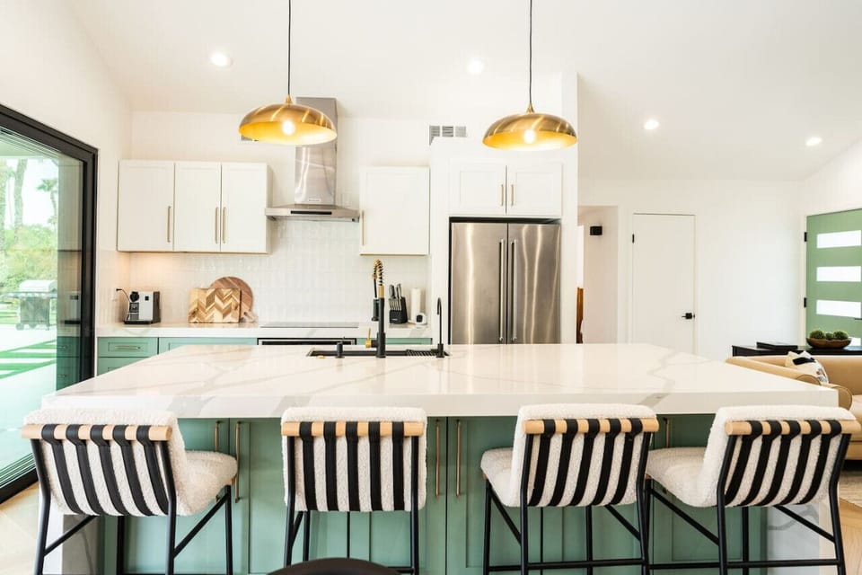 Modern kitchen w/ a large island, bar seating & bright finishes ideal for cooking and casual meals.
