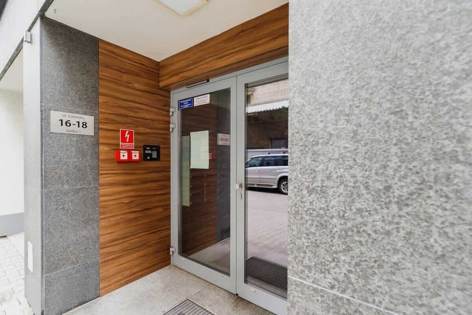 A modern entrance to the building featuring a sleek glass door, wooden paneling, and a security system, ensuring safety and a stylish first impression.
