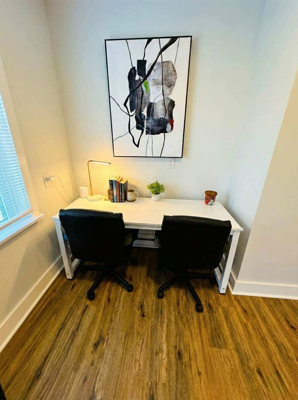 Dedicated workspace with desk, two chairs, window light, and wall art.
