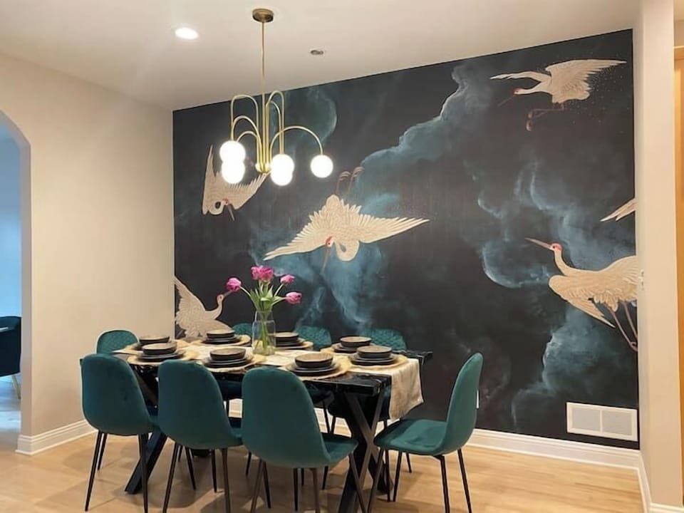 Elegant dining area with statement crane mural and modern chandelier.