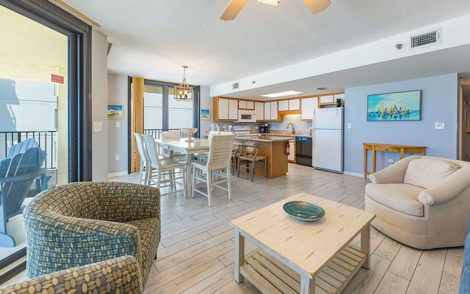 Dining area featuring a whitewashed table and chairs, with sliding doors opening to a beach balcony