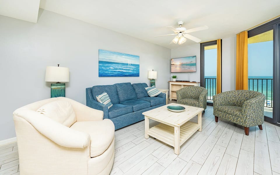 Bright living area features a blue sofa with queen sleeper, patterned chairs, and a dining table