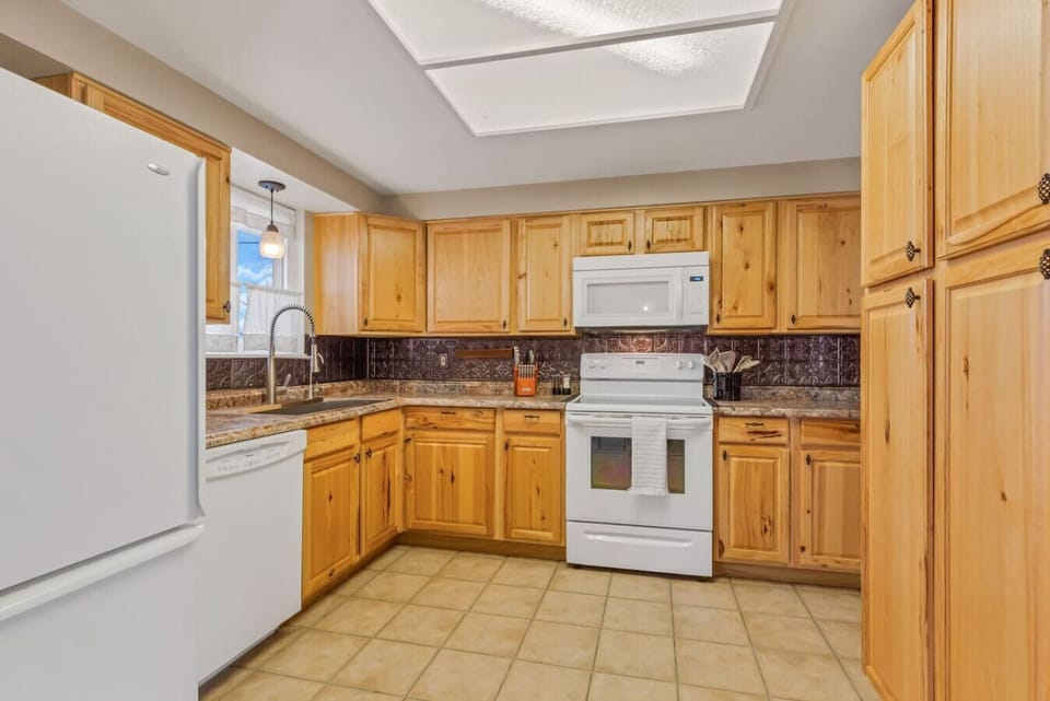 Step into the heart of the home: the kitchen boasts tiled floors, ample cupboards, and base cabinets, offering both style and functionality for culinary adventures and organization alike.