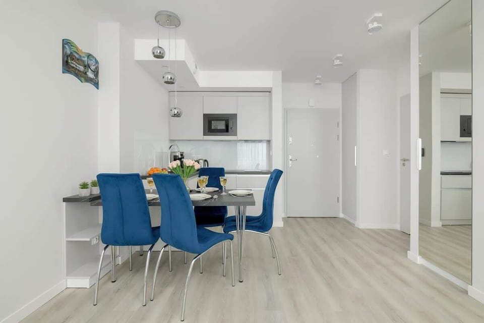 A bright and elegant kitchen and dining area with blue chairs and a minimalist aesthetic.

