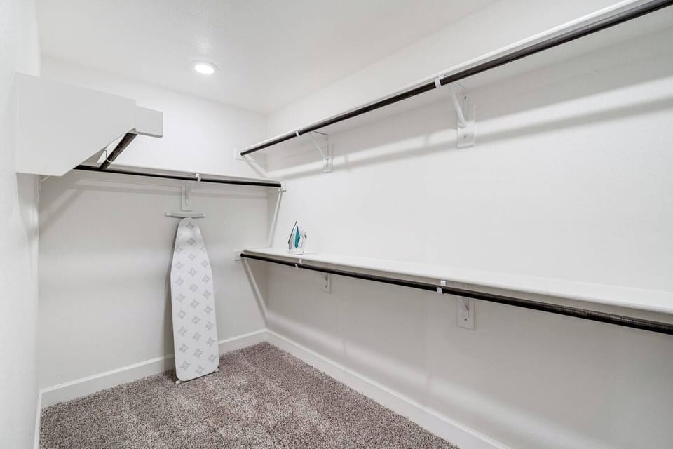 Spacious walk-in closet equipped with an ironing board and iron, providing convenience for all your wardrobe needs.

