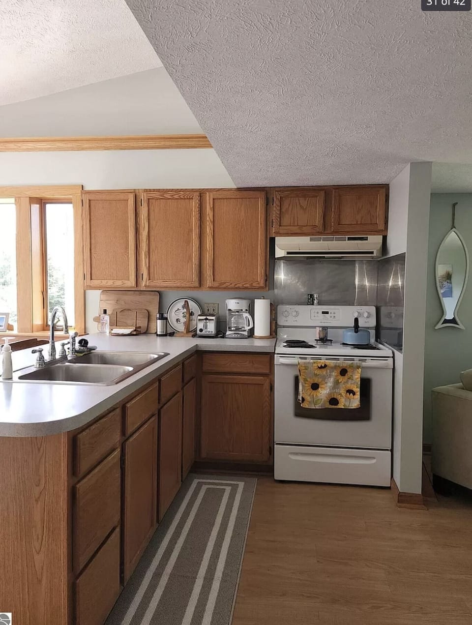 House kitchen has island, dining table, and  electric stove. 