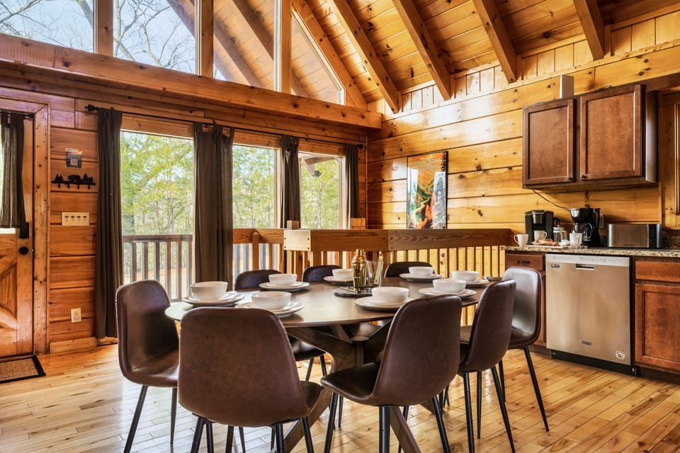 Open space kitchen and dining area with Cathedral ceiling and wooden views.