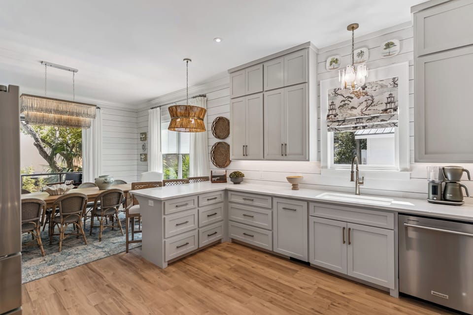 Your modern kitchen invites culinary adventures with sleek gray cabinets, stainless appliances, and coastal charm that flows into the dining nook.