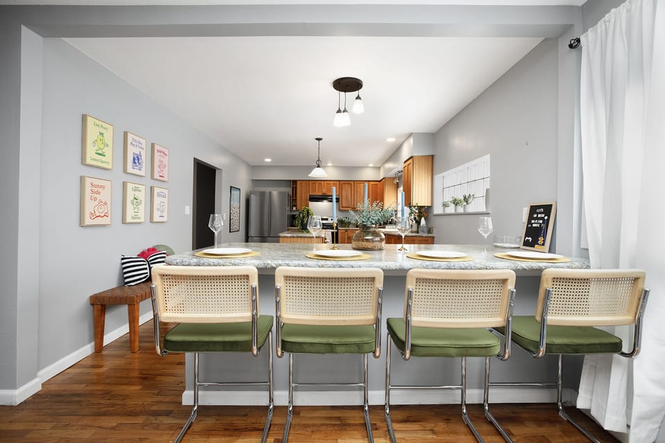 Dining room with playful art and modern kitchen view.