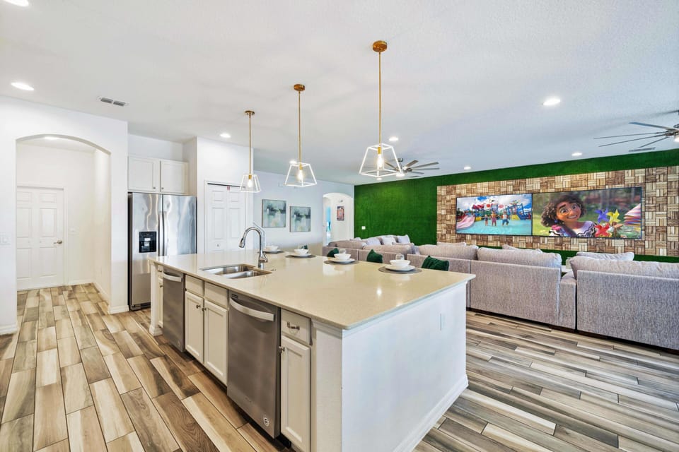 - Modern kitchen with island seating and bright open design  
- Overlooks family living room with entertainment wall setup  
- Orlando vacation rental with chef-ready kitchen near Disney
