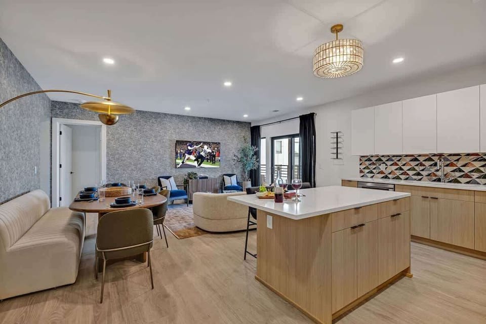 The fully equipped modern kitchen features culinary essentials, stainless steel appliances, and island bar seating.