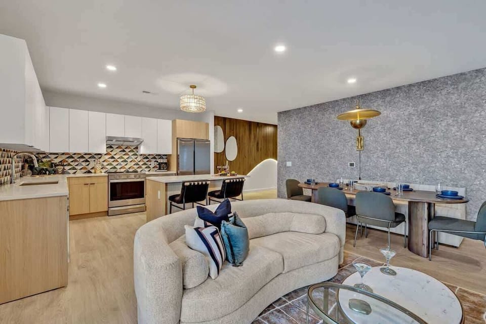 Bright open living space featuring smart flat-screen TV, designer furnishings, and access to a large corner private balcony.