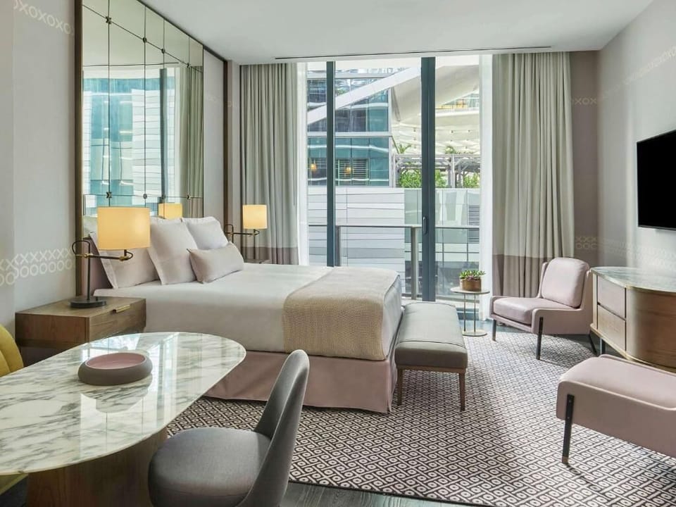 Unwind in a sunlit suite with plush bed and seating.