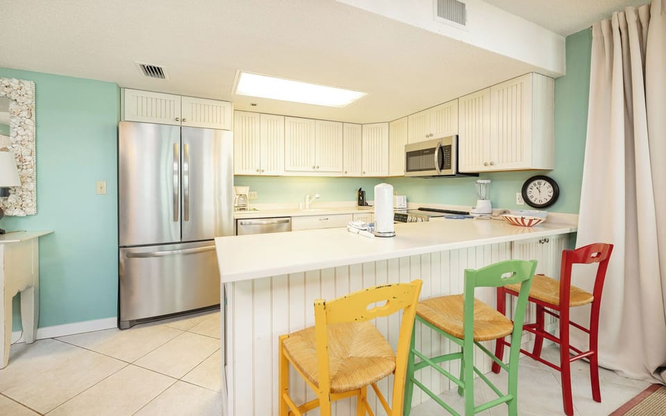This kitchen invites you to chat around the breakfast bar with colorful stools after a day at the coast