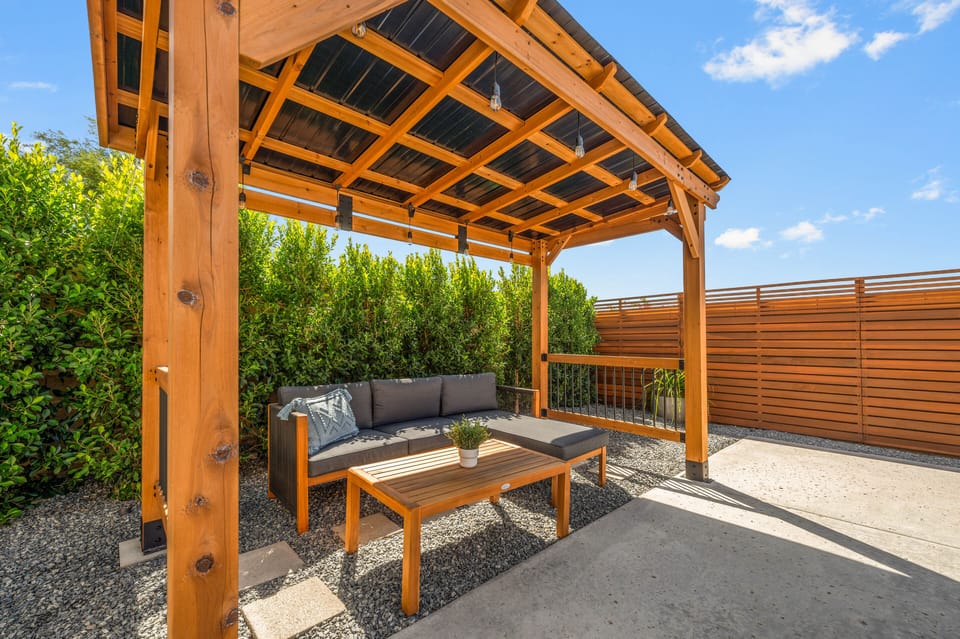 Wood pergola offers shade and a comfortable couch, with lush greenery