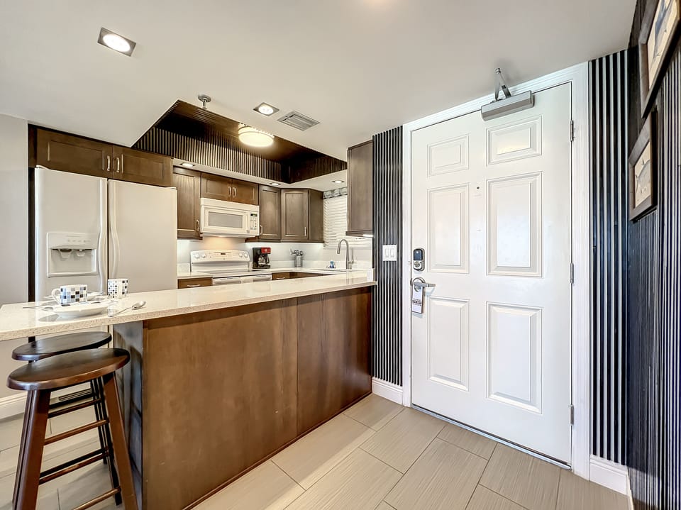 Step into this modern kitchen with stylish cabinetry, spacious countertops, and stainless appliances, perfect for whipping up meals after a day at the beach.
