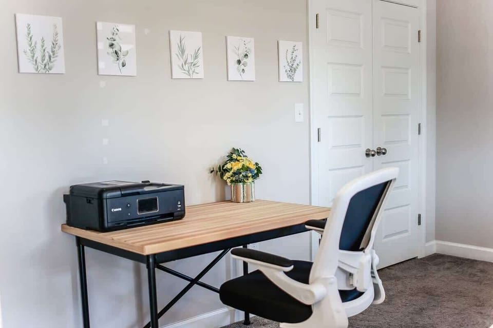 Office desk, office chair, printer and artwork in the bedroom. 