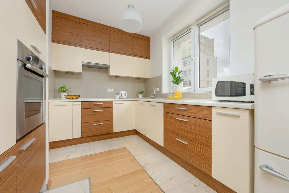 A bright and functional cooking space with wooden cabinetry, stainless steel appliances, and a decorative touch of greenery.

