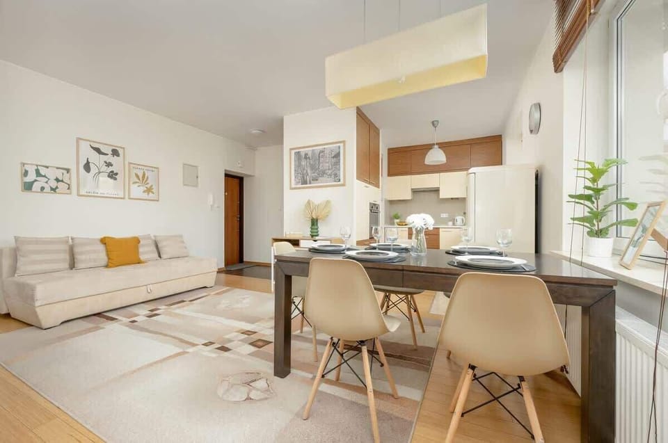A beautiful dining setup with a wooden table, neutral-toned chairs, and a soft lighting fixture, perfect for hosting guests.

