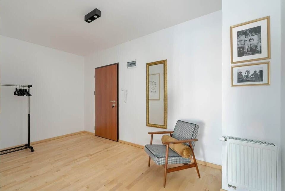 A spacious hallway with a modern chair, framed artwork, and soft lighting, adding to the refined ambiance of the apartment.
