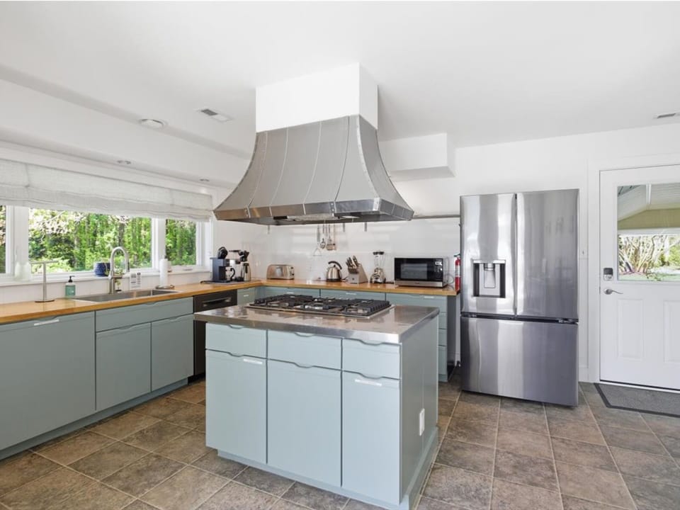 Your spacious kitchen invites culinary adventures with modern stainless steel appliances, a central island for prep, and garden views.